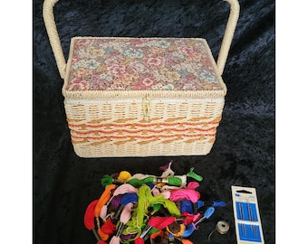 May include: A vintage sewing basket with a floral patterned lid and a woven wicker body. The basket has a handle and is filled with colourful embroidery floss, needles, and a bobbin. The basket is approximately 25 cm long.