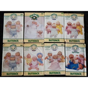 Könnte beinhalten: Eine Sammlung von Vintage-Butterick-Schnittmustern für Cabbage Patch Kids-Kleidung. Die Muster zeigen Illustrationen der Puppen in verschiedenen Outfits, mit dem Butterick-Logo und den Musternummern.