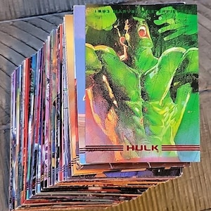 Könnte beinhalten: Ein Stapel Vintage Marvel Sammelkarten mit dem Hulk. Die oberste Karte zeigt eine grüne Hulk-Illustration mit dem Text "HULK" und "1993 MARVEL". Die Karten haben farbenfrohe Kunstwerke.