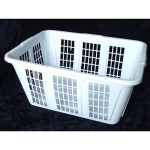 Puede incluir: Una cesta de lavandería rectangular de plástico blanco con un patrón de ventilación de rejilla en los cuatro lados y una base sólida. La cesta tiene un borde ancho y reforzado en la parte superior y soportes estructurales verticales.