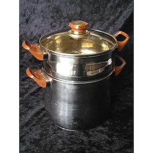 May include: A stainless steel cooking pot with a glass lid and wooden handles. The pot has a two-tiered design, with a smaller pot stacked on top of a larger one. The lid and handles are a warm brown colour.
