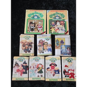 Op de afbeelding: Een verzameling vintage Cabbage Patch Kids naaipatronen en boeken. De patronen zijn van Butterick en bevatten verschillende outfits. De boeken heten "Pony & Western Wear" en "Designer Clothes."