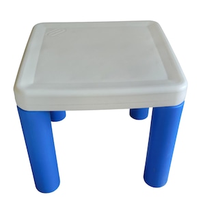 May include: A square table featuring a white plastic top with rounded corners and four thick, cylindrical blue plastic legs. The surface of the table is smooth and flat, providing a stable base, while the legs are positioned at each corner.