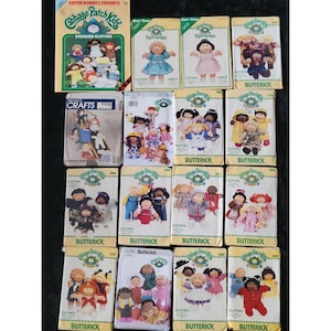 May include: A collection of vintage Cabbage Patch Kids sewing patterns and a designer clothes book. The patterns feature illustrations of the dolls in various outfits. The book cover reads "Cabbage Patch Kids Designer Clothes".