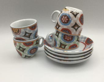 Pode incluir: Conjunto de quatro xícaras de espresso e pires coloridos com padrões geométricos e florais. As xícaras estão empilhadas umas sobre as outras e os pires estão empilhados por baixo.