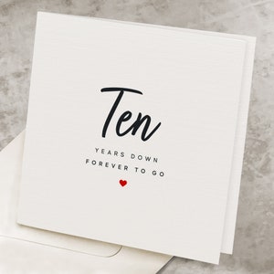May include: White card with black text that reads "Ten Years Down Forever To Go" with a small red heart below the text.