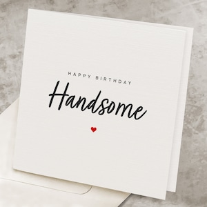May include: White card with black text that says "Happy Birthday Handsome" with a small red heart below the text.