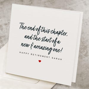 May include: A square, off-white retirement card with black script that reads "The end of this chapter, and the start of a new & amazing one!" Below, it says "HAPPY RETIREMENT SARAH" with a small red heart.