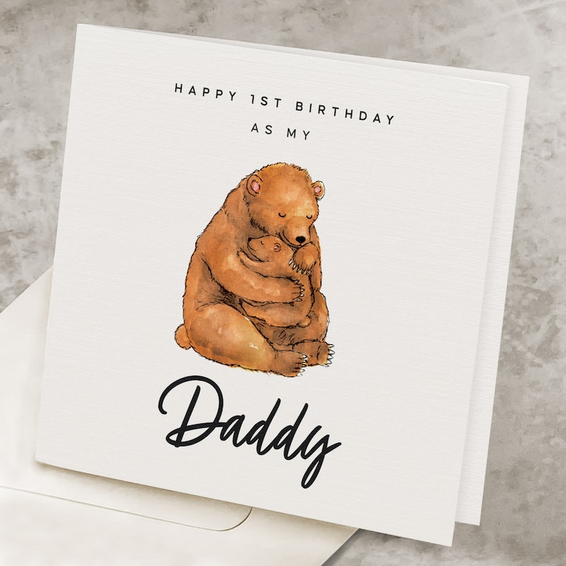 Puede incluir: Una tarjeta blanca con el texto "Happy 1st Birthday as my Daddy" en letras negras. Una ilustraci&oacute;n de acuarela de un oso marr&oacute;n abrazando a un oso marr&oacute;n m&aacute;s peque&ntilde;o.