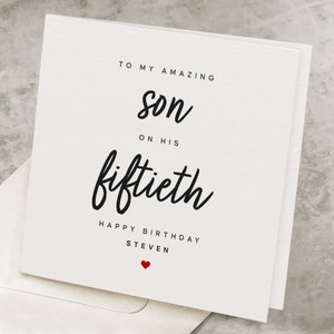May include: A white card with black text that reads "To my amazing son on his fiftieth Happy Birthday Steven" with a small red heart at the bottom.