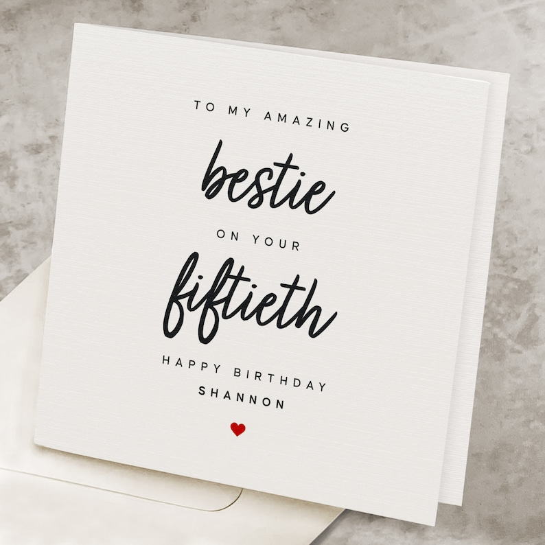 Puede incluir: Una tarjeta blanca con texto negro que dice "To my amazing bestie on your fiftieth Happy Birthday Shannon" con un peque&ntilde;o coraz&oacute;n rojo en la parte inferior.