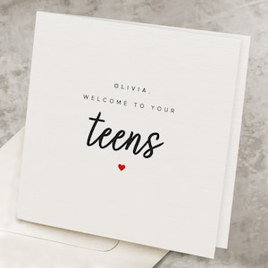May include: A white card with black text that reads "Olivia, Welcome to your teens" with a small red heart below the text.