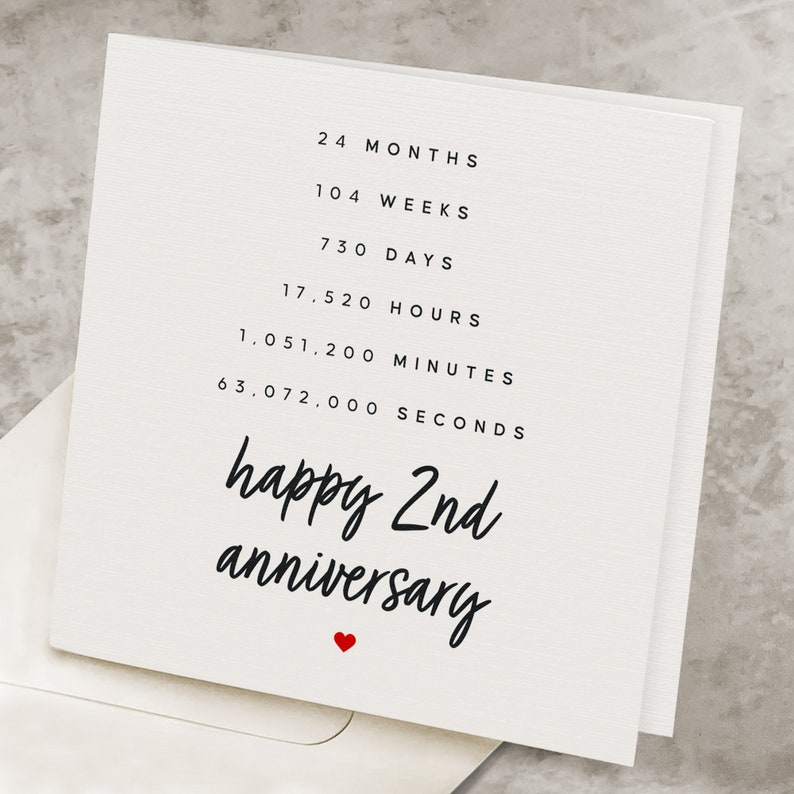 May include: A white card with black text that reads "24 Months, 104 Weeks, 730 Days, 17,520 Hours, 1,051,200 Minutes, 63,072,000 Seconds, happy 2nd anniversary" with a small red heart at the bottom.