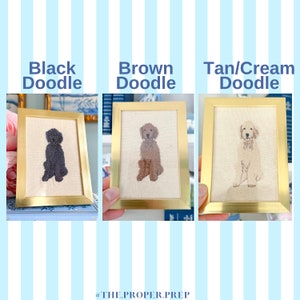 May include: Three framed embroidered pictures of doodle dogs in black, brown, and tan/cream colours. The frames are gold and the background is a blue and white striped pattern.