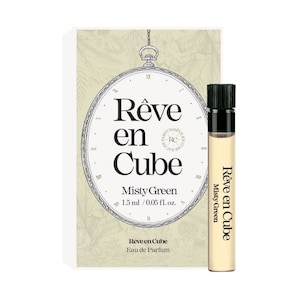 May include: A small bottle of Misty Green perfume by Reve en Cube. The bottle is clear glass with a black cap and a white label with the brand name and scent name. The bottle is 1.5 ml / 0.05 fl. oz.