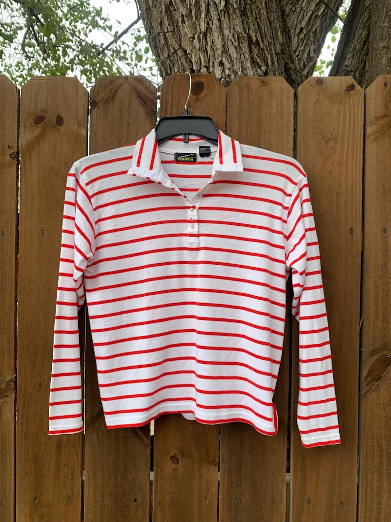 May include: White long-sleeve shirt with red horizontal stripes and a single button closure at the collar. The shirt has a green label with the text "Talbots" on it.