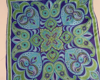 May include: A square silk scarf with a paisley pattern in shades of green, blue, and purple. The design features a central motif of a stylized flower with four petals, surrounded by repeating paisley shapes.