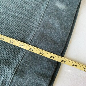May include: Close-up of a dark green fabric with a measuring tape showing 23 to 31 inches.