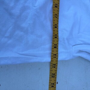 Pu&ograve; includere: Un tessuto bianco con un metro a nastro giallo che mostra misure da 40,6 a 61 cm. Il tessuto &egrave; leggermente stropicciato e sembra far parte di un capo d'abbigliamento.