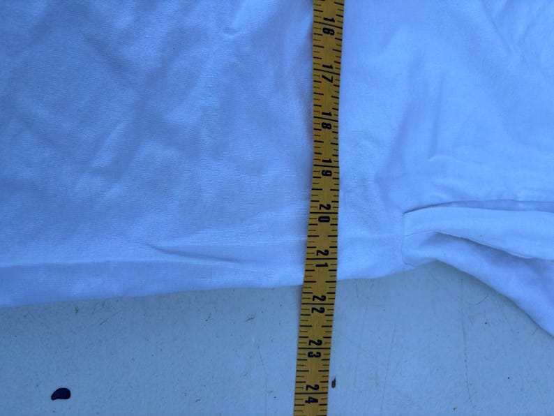 Pu&ograve; includere: Un tessuto bianco con un metro a nastro giallo che mostra misure da 40,6 a 61 cm. Il tessuto &egrave; leggermente stropicciato e sembra far parte di un capo d'abbigliamento.