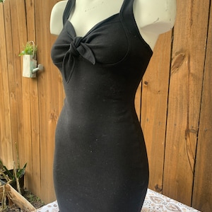 May include: A black sleeveless dress with a bow at the neckline. The dress is fitted and has a short length.