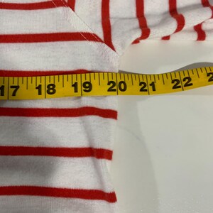 May include: Close-up of a red and white striped shirt with a measuring tape showing 22 inches.