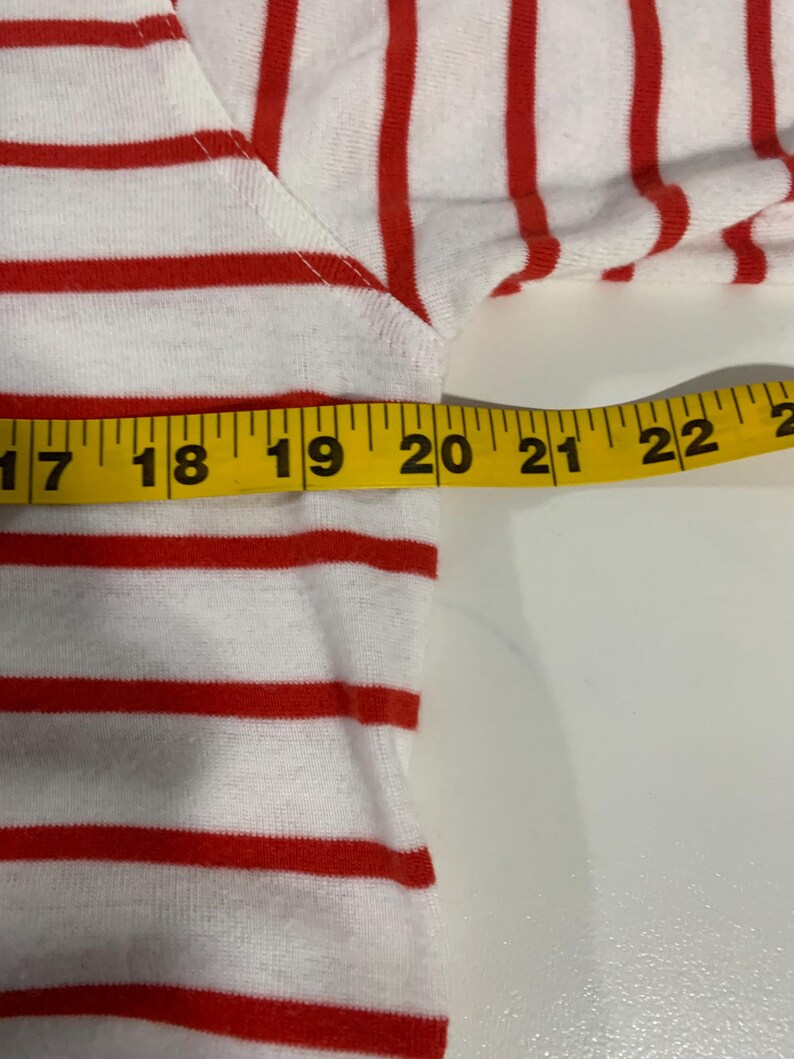 May include: Close-up of a red and white striped shirt with a measuring tape showing 22 inches.