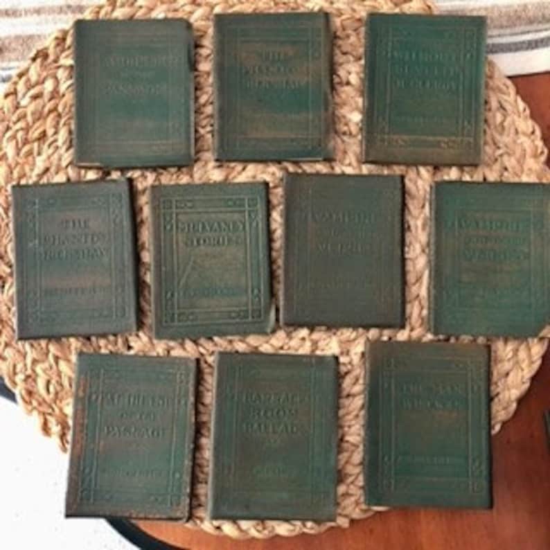 May include: Set of eight small, green leather-bound books with gold lettering on the spines. The books are arranged in two rows of four. The books are all the same size and shape.