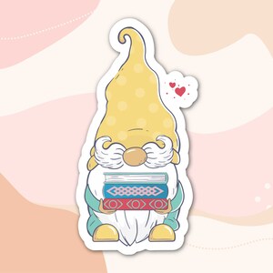 May include: A yellow gnome with a white beard and moustache is holding a stack of books. The gnome is wearing a blue and green outfit and has a red heart above its head.