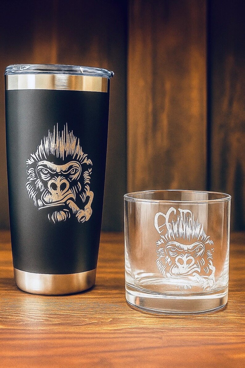 May include: A matte black stainless steel tumbler with a silver rim and a laser-engraved gorilla graphic, paired with a clear glass tumbler featuring the same etched gorilla design. Both containers display a detailed illustration of a gorilla face.