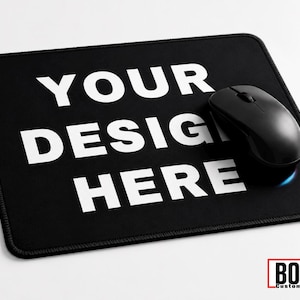 May include: A rectangular black mouse pad with white text that reads YOUR DESIGN HERE. A black computer mouse rests on the right side of the pad. In the bottom right corner, a red-bordered white box contains the black text BOSS Custom Works.