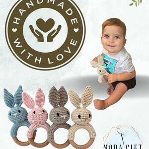 Pu&ograve; includere: Quattro giocattoli sonagli a forma di coniglio all'uncinetto con anelli di legno. I conigli sono blu, rosa, grigi e beige. I giocattoli sono fatti a mano e hanno il testo "Handmade with Love" su un cerchio marrone.