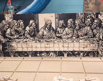 Puede incluir: Una talla de madera en blanco y negro de la Última Cena. La talla está en un panel de madera y está siendo trabajada por una máquina CNC.