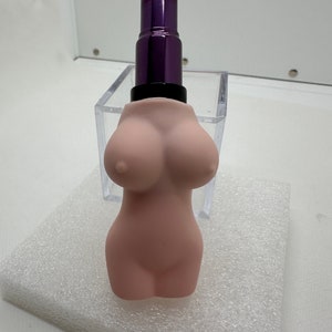 May include: A pink lipstick shaped like a female torso with a purple lipstick tube on top.