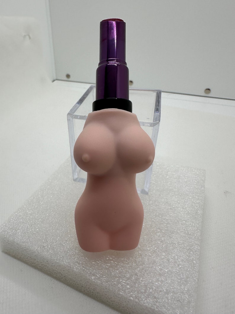May include: A pink lipstick shaped like a female torso with a purple lipstick tube on top.