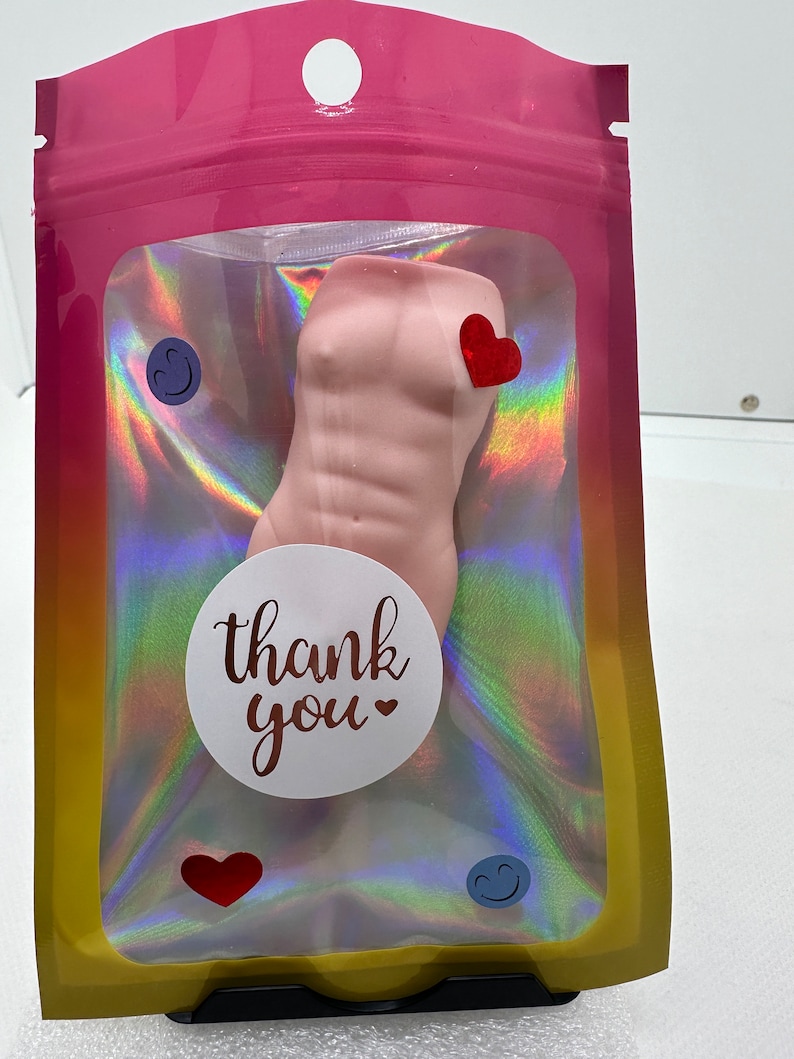 May include: A pink, sculpted torso with a thank you sticker and hearts in a clear plastic bag with a holographic iridescent background.