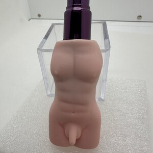 May include: A nude-colored ceramic figurine of a torso with a detailed anatomical design. The figurine is in a clear plastic container.