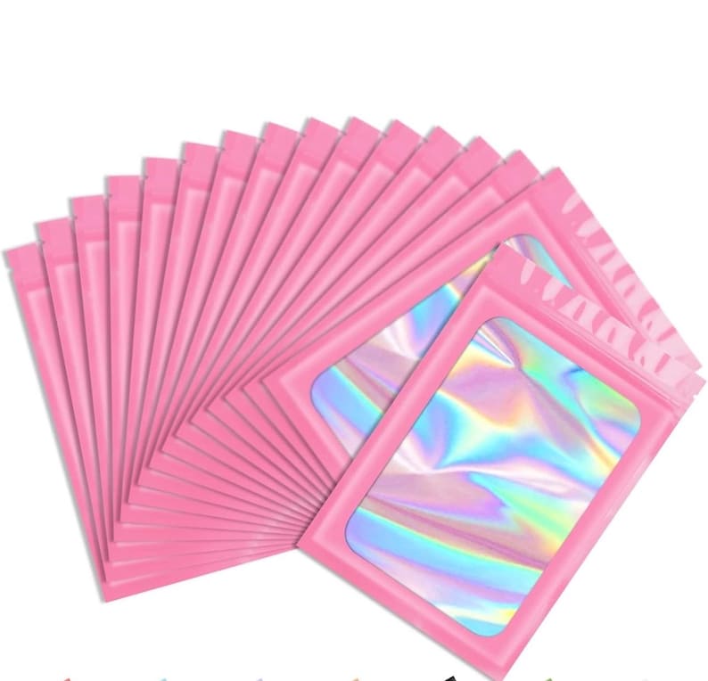 May include: A collection of pink, resealable pouches with a clear, iridescent window. The pouches are arranged in a fan shape, showcasing the holographic effect of the window material. The pink color is consistent across all pouches.