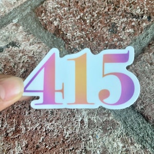 May include: A white sticker with the number 415 in a gradient of pink, orange, and yellow.
