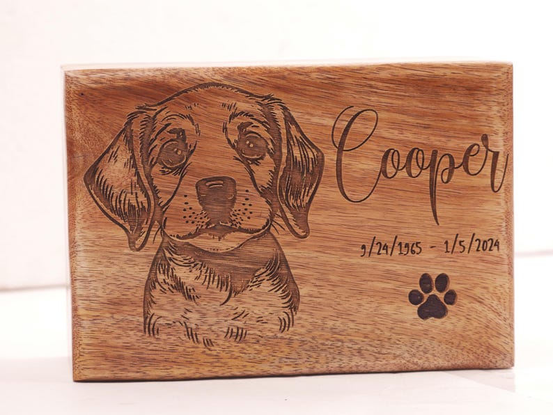 May include: A wooden box with a laser engraved image of a dog and the text "Cooper 9/24/1965 - 1/5/2024" with a paw print below the dates.