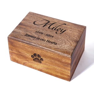 May include: A wooden pet urn with an engraved paw print and the inscription "Miley 2009-2024 Forever in our Hearts".