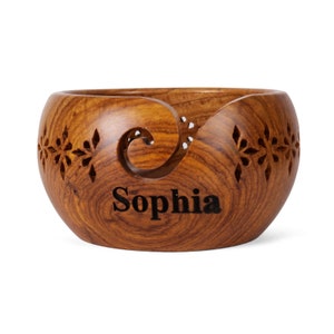 May include: A wooden yarn bowl with a carved design and the name "Sophia" engraved on the front.