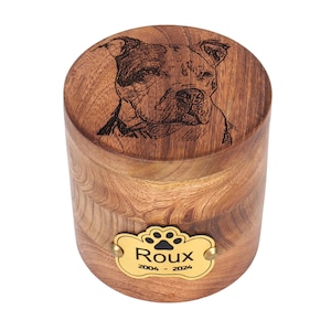 May include: A wooden pet urn with a laser engraved image of a dog and a brass plaque with the name "Roux" and the dates "2004 - 2024".