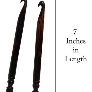 Op de afbeelding: Twee houten haaknaalden met bruin en zwart gestreepte handvatten. Elke haaknaald is 17,78 cm lang.