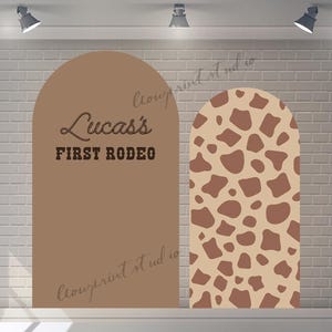 Könnte beinhalten: Zwei braune Bogenhintergründe für eine Fotobox. Ein Hintergrund hat einen braunen und weißen Giraffen-Druck. Der andere Hintergrund hat den Text "Lucas's First Rodeo" in brauner Schrift.