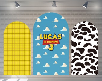May include: Three arch-shaped backdrops for a birthday party. The backdrop on the left is yellow with a grid pattern. The middle backdrop is blue with white clouds and the text "LUCAS IS TURNING 3". The backdrop on the right is white with black cow spots.