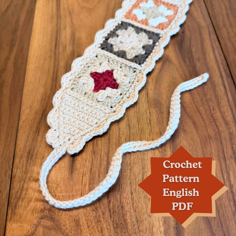 Close-up of a rustic granny square crochet headband with floral motifs and scalloped edging, shown on a wooden surface with tie-back ends and an English crochet pattern PDF label.