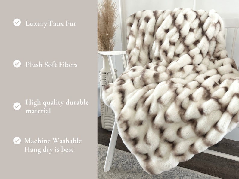 May include: A white and brown faux fur throw blanket draped over a white chair. The blanket has a woven design with plush, soft fibers. The image also includes text that says "Luxury Faux Fur", "Plush Soft Fibers", "High quality durable material", and "Machine Washable Hang dry is best".