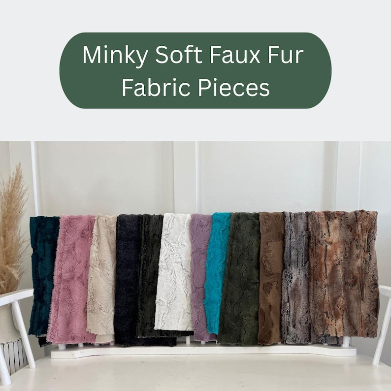 May include: A display of Minky Soft Faux Fur Fabric Pieces in various colors, including teal, pink, beige, black, white, purple, and brown. The fabric has a soft, textured appearance, and the pieces are arranged on a white shelf.