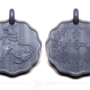 May include: A dark gray, scalloped-edge circular pendant featuring a relief of a mythical lion creature on one side and intricate floral scrollwork surrounding Burmese script text on the reverse, both topped with a small integrated loop.